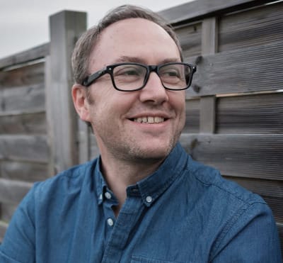 Photo de l'auteur Cyril Vallée devant une palissade en bois.