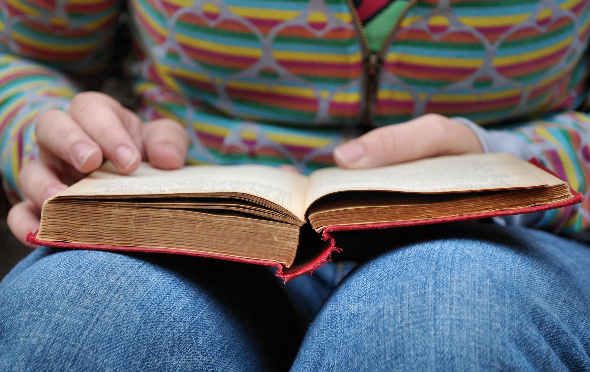 Un livre ouvert, posé sur le genoux d'une personne assise.