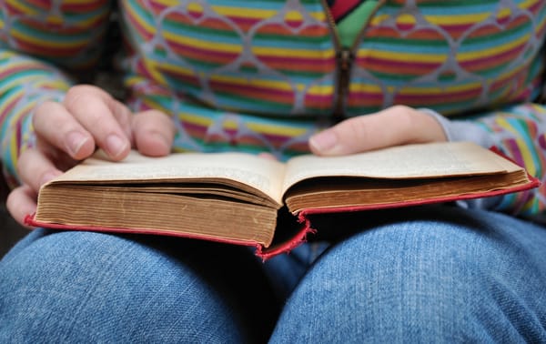 Un livre ouvert, posé sur le genoux d'une personne assise.